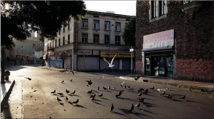  ?? JAE C. HONG — THE ASSOCIATED PRESS ?? Birds eat bread crumbs on an empty street. The 2020corona­virus pandemic is not a sign of the end of the world, Christians say.