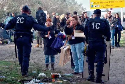  ?? AFP ?? French policemen talk to volunteers in the ‘Jungle’ migrant camp in Calais on Thursday during a massive operation to clear the squalid settlement where 6,000-8,000 people have been living in dire conditions. —