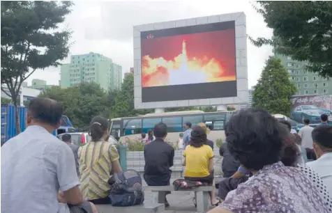  ?? — AFP ?? People watch as coverage of an ICBM missile test is displayed on a screen in a public square in Pyongyang on Saturday.