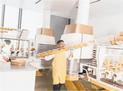  ?? Photos by Cayce Clifford / Bloomberg ?? A worker refills the buns at Creator, which is about to start offering its automated burgers South of Market.