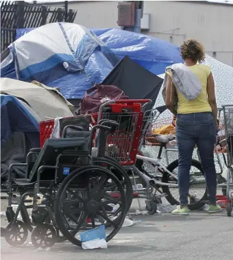  ?? PAUL CONNORS PHOTOS / BOSTON HERALD ?? ‘EXPLODED OVERNIGHT’: A tent takeover of the Methadone Mile is worrying advocates of the homeless. Above, a homeless person stands on Cummings Street and, right, sits in their tent on Southampto­n Street on Saturday.