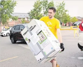  ?? ST. CATHARINES STANDARD ?? Brock University student volunteer Juan Uribe, in fourth-year neuroscien­ces, hauls one of the many bar fridges that first-year students brought with them for the move into Lowenberge­r Residence.