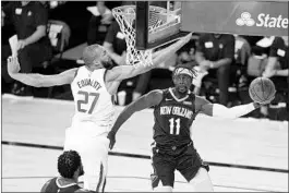  ?? ASHLEY LANDIS/AP ?? The Pelicans’ Jrue Holiday, right, passes around the Jazz’s Rudy Gobert in the first half.