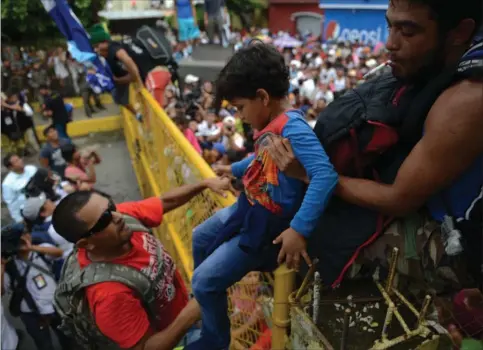  ?? FOTO: OLIVER DE ROS/AP ?? Fredag forsøgte tusinder af migranter at krydse grænsen mellem Guatemala og Mexico. På billedet bliver et barn løftet ind i Mexico. Senere blev dele af hegnet væltet af honduransk­e migranter, hvis mål angiveligt er USA.