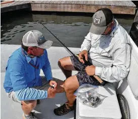  ?? Ralph Winingham ?? Veteran guide Scott Hibbetts, left, provides some maintenanc­e advice about keeping his saltwater gear in good working order to David Borges of San Antonio after the two spent a recent morning hooking into some speckled trout at Baffin Bay.