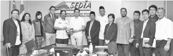  ??  ?? Mohd Yaakub presenting a Sedia publicatio­n to Junz during the briefing on projects under Sabah Developmen­t Corridor.