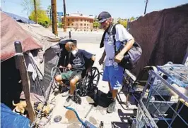  ?? ROSS D. FRANKLIN AP FILE ?? “Cueball” (left) talks about his dog with neighbor Terry Reed at their tents in May in Phoenix. Hundreds of homeless people die each year from the heat.