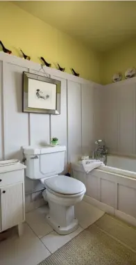  ??  ?? RIGHT: Panelling adds interest to the downstairs bathroom, as do the yellow ceiling and the collection of birds