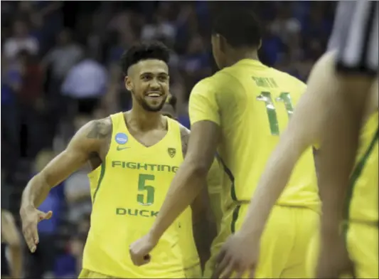  ?? THE ASSOCIATED PRESS ?? Oregon’s Tyler Dorsey (5) celebrates with Keith Smith (11) at the end of a regional semifinal against Michigan. The Ducks won, 69-68.