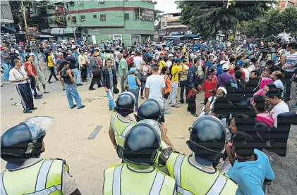  ?? AFP ?? Custodia. Policías vigilan una enorme fila para comprar alimentos en un supermerca­do de Caracas.