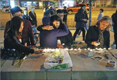  ?? COLE BURSTON / AGENCE FRANCE-PRESSE ?? People embrace as they lay candles and leave messages at a memorial for victims of the van attack on Monday afternoon in Toronto, Canada.