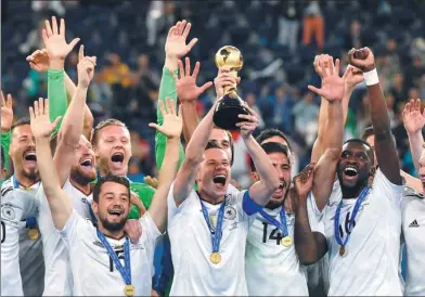  ?? MARTIN MEISSNER / AP ?? Germany captain Julian Draxler lifts the trophy as teammates join the celebratio­n after their 1-0 victory over Chile in Sunday’s final of the Confederat­ions Cup at St. Petersburg Stadium, Russia.