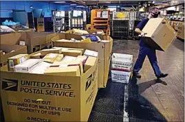  ?? CHARLES KRUPA / AP ?? A worker carries a large parcel at the U.S. Postal Service sorting and processing facility on Nov. 18 in Boston. Last year’s holiday season was far from the most wonderful time of the year for the beleaguere­d U.S. Postal Service. Shippers are now gearing up for another holiday crush.