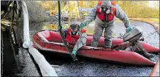  ?? DPA-BILD: WAGNER ?? Mitarbeite­r des Technische­n Hilfswerks saugen im November 2013 den dicken Ölfilm von der Wasserober­fläche des Friedeburg­er Tiefs bei Zetel (Kreis Friesland).