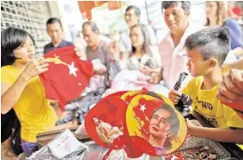  ?? Gemunu Amarasingh­e / Associated Press ?? People scramble to buy merchandis­e with pictures of Myanmar opposition leader Aung San Suu Kyi, whose party appears headed for a massive election victory.