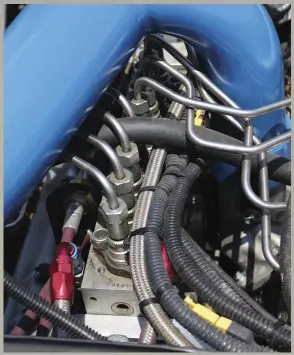  ??  ?? Beneath the cold-side water-to-air intercoole­r piping lies the magic behind the mechanical 7.3L: the P-pump. Hypermax treated the Bosch inline pump to 13 mm plungers and barrels, a hot-rod cam, and an Ag governor that provides full fueling all the way up to 5,800 rpm. The P-pump sends fuel through specially-bent injection lines to eight injectors similar in appearance to what you’d find in a DT466 Internatio­nal. Hypermax’s injector adapter sleeves simplified the process of converting the injector style from HEUI to mechanical without requiring extensive additional machining of the heads.