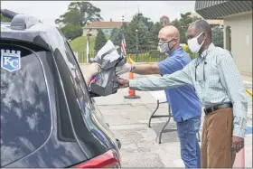  ?? NATI HARNIK — THE ASSOCIATED PRESS ?? A motorist is handed a bag containing informatio­n about open positions at a drive-thru job fair in Omaha, Neb., on Wednesday. Nebraska reinstated job search requiremen­ts this week for most people claiming jobless benefits. Those unemployme­nt insurance requiremen­ts were suspended in mid-March to help employees who had lost their jobs due to the coronaviru­s.