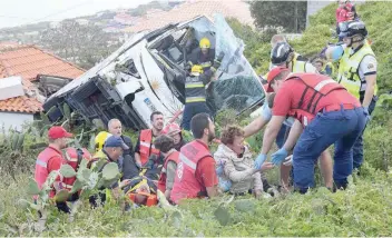  ?? — AFP ?? Firemen help victims of a tourist bus that crashed in Caniço, on the Portuguese island of Madeira.