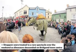  ??  ?? > Shoppers were treated to a rare spectacle over the weekend as dinosaurs descended on Bridgend town centre