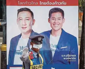  ?? EPA PIC ?? A security guard standing next to an electoral poster with the portraits of Thai Raksa Chart party's leader Preechapol Pongpanich (right) and its party's member of parliament constituen­cy candidate in Bangkok yesterday.