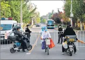  ?? REUTERS ?? Medical workers ride past an entrance to an area under lockdown in Beijing, China, on Thursday.