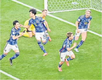  ?? — AFP photo ?? Japan’s players rush to celebrate their team’s first goal during the Qatar 2022 World Cup Group E match between Germany and Japan at the Khalifa Internatio­nal Stadium in Doha. Japan defeated Germany 2-1 in a World Cup shock late last night as Takuma Asano’s 83rd minute winner stunned the four-time champions. Ilkay Gundogan had given Germany a first-half lead from the penalty spot before Ritsu Doan equalised in the 75th minute, giving Japan the chance to set up a famous winning goal.