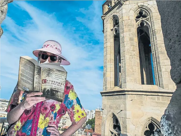  ?? XAVIER CERVERA ?? Un turista lee La catedral del mar desde un punto elevado de Santa Maria del Mar, escenario de la novela, zona que se ha abierto al público a raíz del éxito del libro