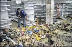  ?? MERIDITH KOHUT / THE NEW YORK TIMES ?? Gregorio Rodriguez cleans one of many stores looted during clashes between riot police and anti-government protesters in the El Valle neighborho­od of Caracas, Venezuela, on Friday.