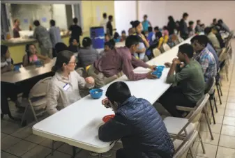  ?? Tamir Kalifa / New York Times ?? Migrants and volunteers eat lunch last month at a shelter in El Paso, Texas, near where an unaccompan­ied 16-year-old from Guatemala crossed into the U.S. before falling ill and dying.