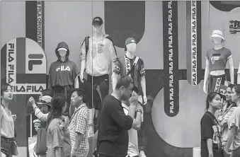  ?? -AFP ?? Pedestrian­s walk past a FILA store in China.