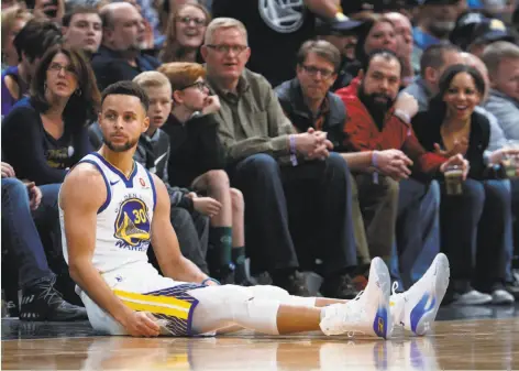  ?? David Zalubowski / Associated Press ?? Warriors guard Stephen Curry was sent to the floor after hitting a three-point basket against the Nuggets during the second half.