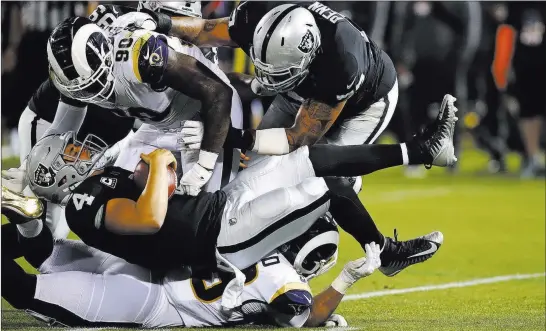  ?? Ben Margot ?? The Associated Press Raiders quarterbac­k Derek Carr (4) is brought down by Los Angeles Rams defensive tackle Michael Brockers (90) in a 33-13 loss Monday night in Oakland, Calif.