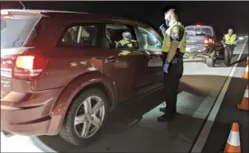  ?? The Maui News / LILA FUJIMOTO photo ?? DUI Task Force officer Caleb Guariello checks on a vehicle stopped at the second Hannah Brown Memorial Intoxicati­on Checkpoint on Wednesday night on Kuihelani Highway. Police screened 192 vehicles and issued eight citations, including three for driving without a license, two each for no insurance and no licensed driver present and one for a child restraint violation.