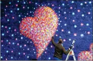  ?? ASSOCIATED PRESS ?? Australian street artist James Cochran works on a mural commemorat­ing the eight victims of the June 3, 2017, London Bridge terrorist attack on a Network Rail wall at Borough Market in London on March 26.