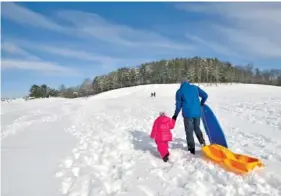  ?? DAVID CRIGGER/THE BRISTOL HERALD-COURIER VIA AP ?? Scott Lay walks with his daughter, Sofia, to a hill at King University in Bristol, Tennessee, to enjoy an afternoon of sledding Monday.