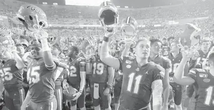  ?? JOHN RAOUX/AP ?? UF quarterbac­k Kyle Trask joins in a celebratio­n with fans after the Gators 40-17 rout of rival Florida State on Nov. 30.