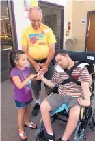  ?? COURTESY OF PATTY WESTERFIEL­D ?? Volunteer Kylie Wood, left, and participan­t Patrick France, right, share a moment with Patrick’s adoptive father, Casey Denholland­er, at Vacation Bible School.