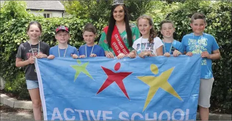  ??  ?? Strawberry Queen Ciara Byrne raises the Active Flag over St Mary’s NS. She is pictured with pupils at the school and the Active Schools Committee.