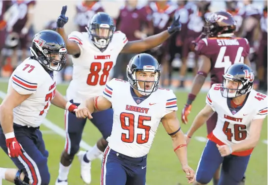  ?? MATT GENTRY/ASSOCIATED PRESS ?? Liberty’s Alex Barbir, center, celebrates after kicking a game-winning 51-yard field goal with one second left to defeat Virginia Tech on Saturday at Lane Stadium.