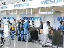  ?? JOHN LUCAS/ POSTMEDIA NEWS ?? WestJet passengers check at Edmonton Internatio­nal Airport. The airline says a $ 25 baggage fee will apply to new economy bookings for flights as of Jan. 6.