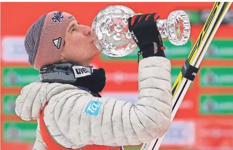  ?? FOTO: AP/DPA ?? Karl Geiger küsst die kleine Kristallku­gel, die er für den Sieg im Skiflug-Weltcup bekomme hat.
