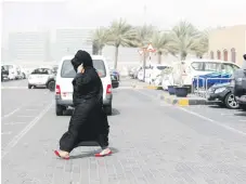  ?? Victor Besa / The National ?? A woman in Abu Dhabi’s Khalifa City takes shelter from dust, which was stirred up across the country