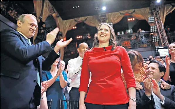  ??  ?? Jo Swinson stands to the applause of Sir Ed Davey, left, the rival candidate, and Duncan Hames, right, her husband, after she was announced as the new leader of the Liberal Democrats at an event in central London
