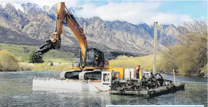  ?? PHOTOS: BOFFA MISKELL ?? Heavy duty . . . An excavator on a barge removes submerged trees from the Kawarau River near Frankton.