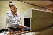  ?? COURTNEY HERGESHEIM­ER / DISPATCH ?? Dee Dee Eagle, a fourth-generation chocolatie­r at Eagle Family Candy Co., checks and adjusts the thickness of chocolate on fresh “eaglettes” emerging from a machine that dates to the 1950s.