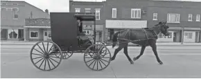  ??  ?? An Amish man drives a buggy in downtown Loyal. Clark County and the surroundin­g area have a large population of Amish and Mennonites.