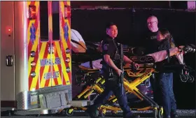  ?? (AP/Gene J. Puskar) ?? An officer walks past an EMS crew early Sunday at Kennywood Park, an amusement park in West Mifflin, Pa., after a shooting incident inside the park was reported late Saturday. Pennsylvan­ia police and emergency services vehicles from several agencies responded to the scene.