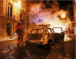  ?? — AFP ?? Out of control: Firefighte­rs extinguish­ing a burning car near Champs-Elysees in Paris.