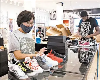  ?? BRIAN CASSELLA/CHICAGO TRIBUNE ?? Anna Kim sorts merchandis­e with shoe store employee Staffone Dodson last week that had been ransacked by looters at Dream Town along Madison Street in West Garfield Park.