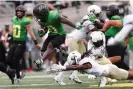  ?? Photograph: Amanda Loman/AP ?? Oregon running back Bucky Irving, left, dodges a tackle by Colorado’s Cam’Ron Silmon-Craig, center, and LaVonta Bentley, right, during the first half of Saturday’s game.